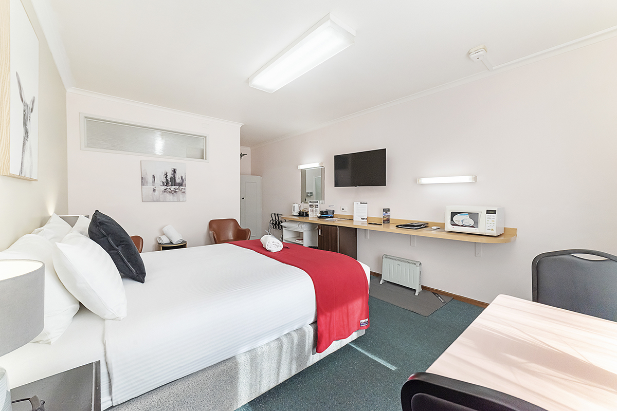 Queen room with red bed runner and guest facilities at City Heart Motel Warrnambool