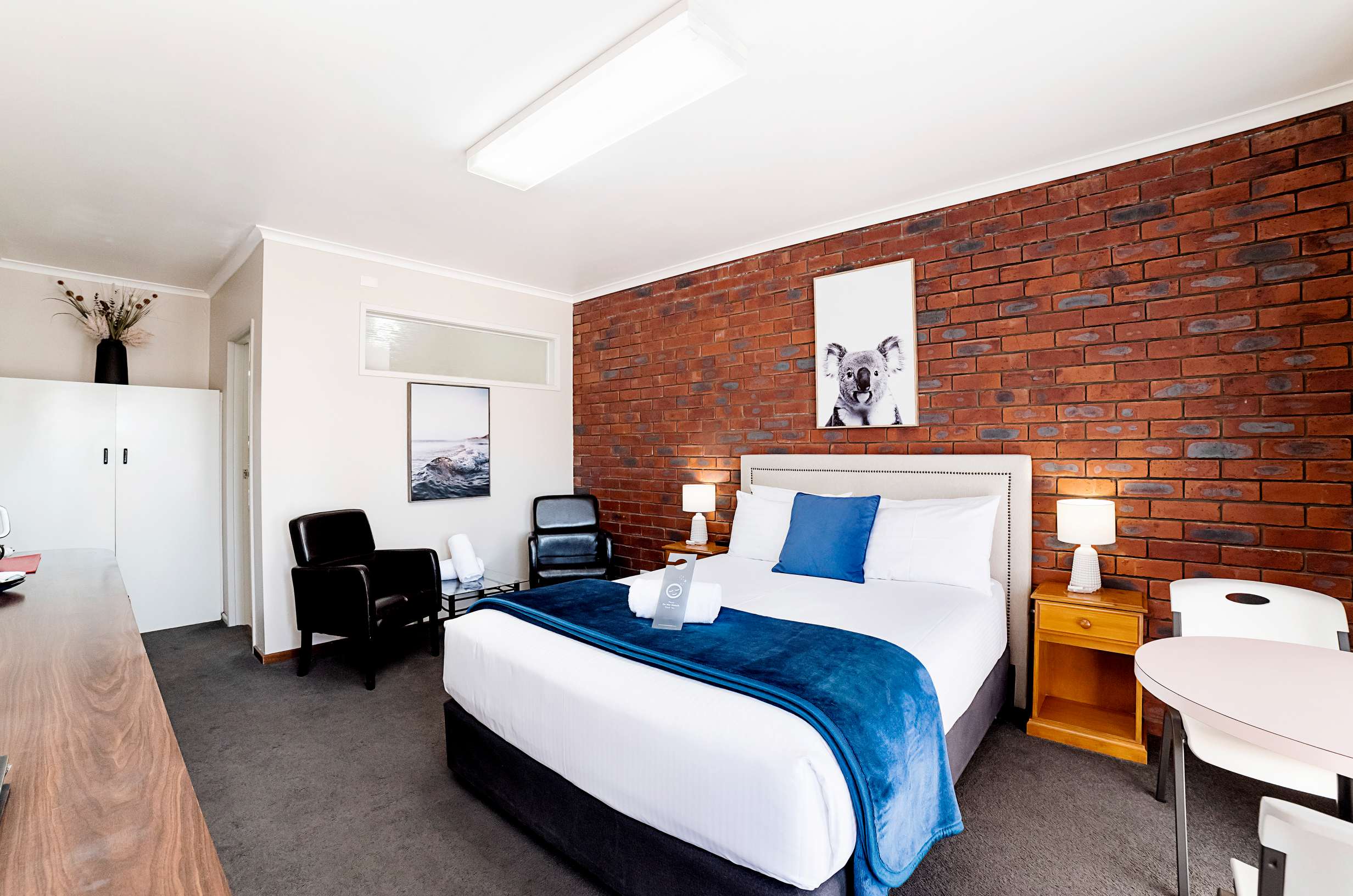 Queen room with brick feature wall and blue bed runner at City Heart Motel Warrnambool